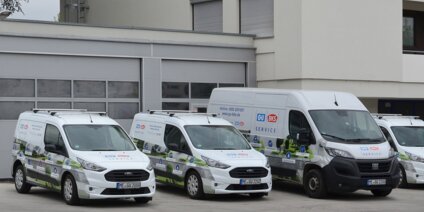 Weiße Servicefahrzeuge vor modernem Betriebsgebäude